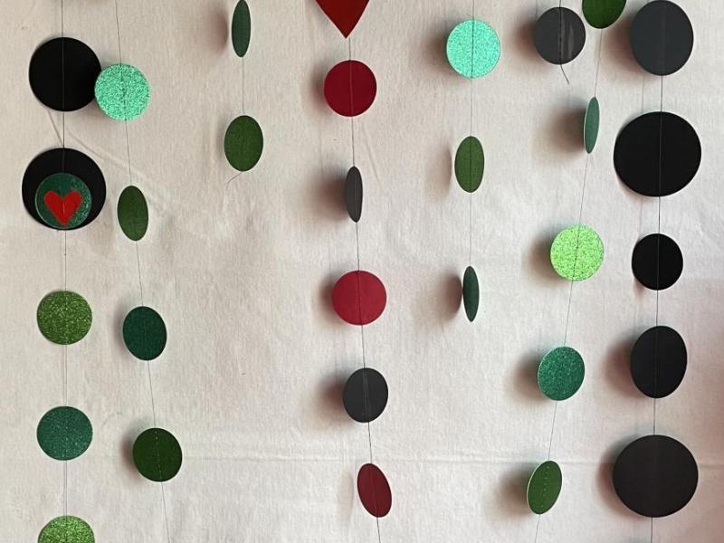 Installation created out of red, black, and green paper, plastic, wire and wood.