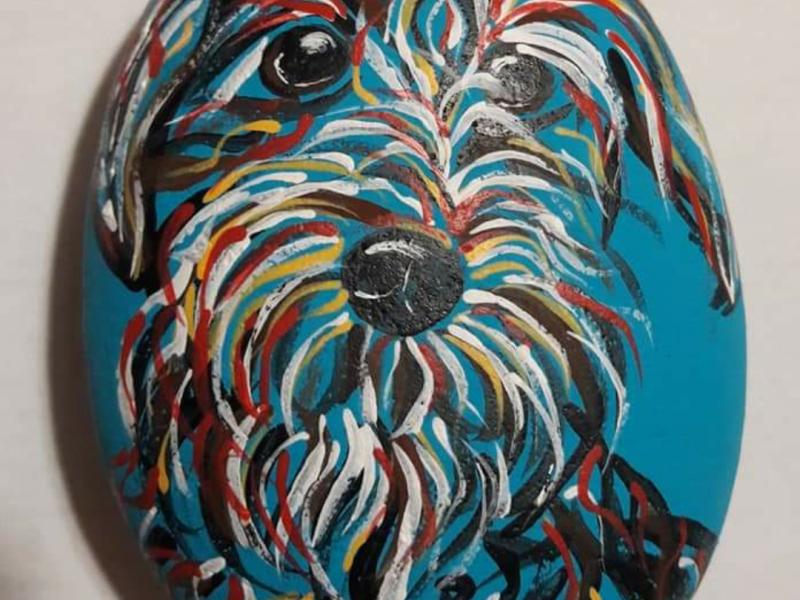 Abstract dog painted with acrylics on rock in multiple colors.