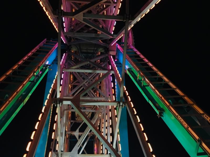 A view of the lit-up structure of the ferris wheel at night while riding the ferris wheel