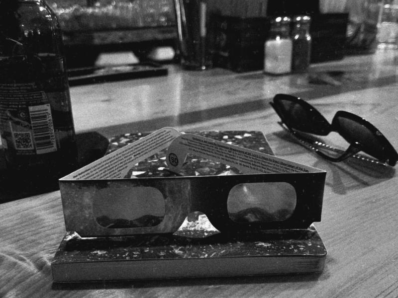 black and white image of solar eclipse glasses sits on a counter