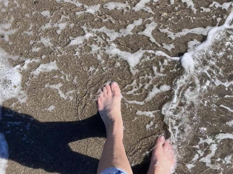 feet in the ocean casting a shadow
