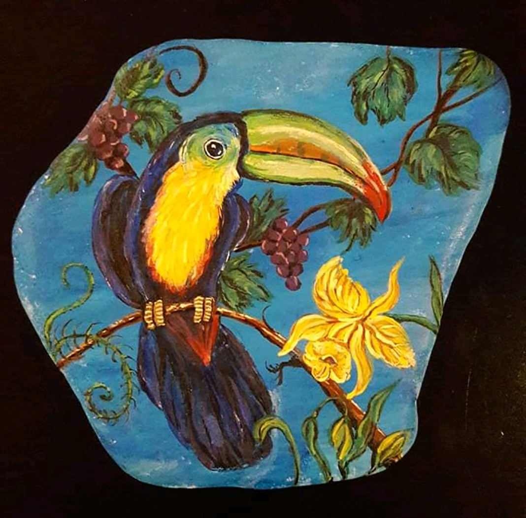 Colorful toucan, berries and flowers painted on Santorini stone.