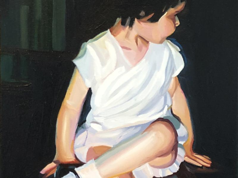 A two year old mid century girl dressed in white. She's turning away from the camera and wearing black Mary Janes.  The background is black. 